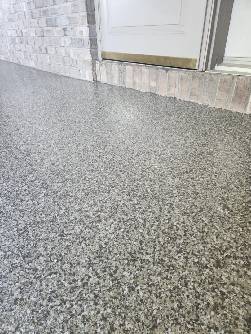 A floor with a gray speckled finish and a door.