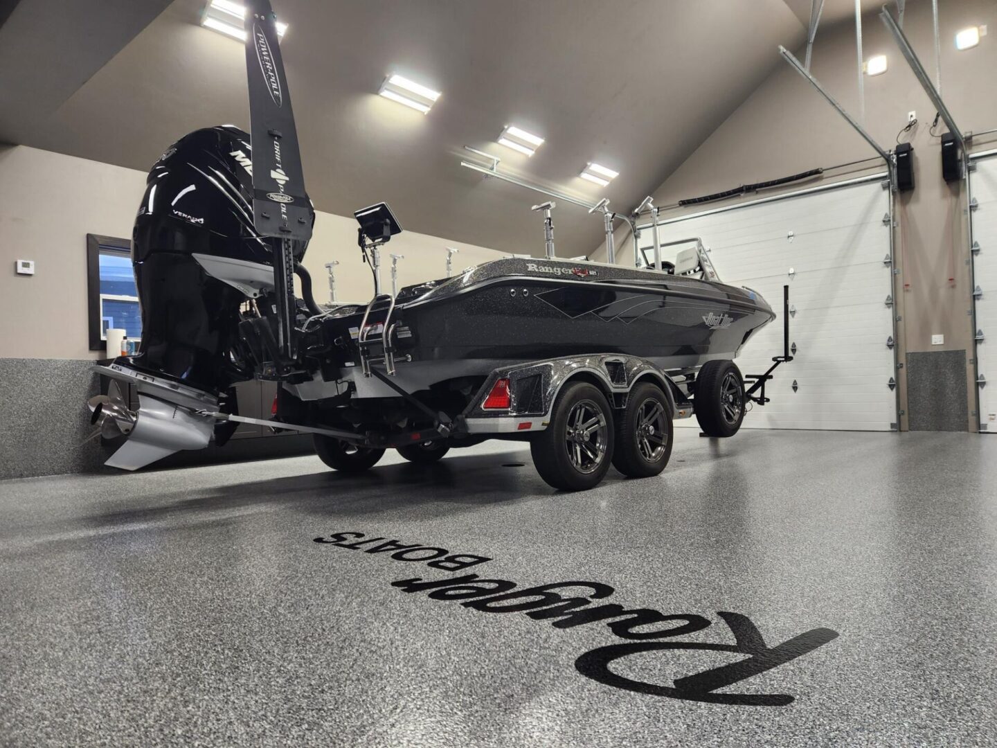 A boat is parked in the garage with its trailer.