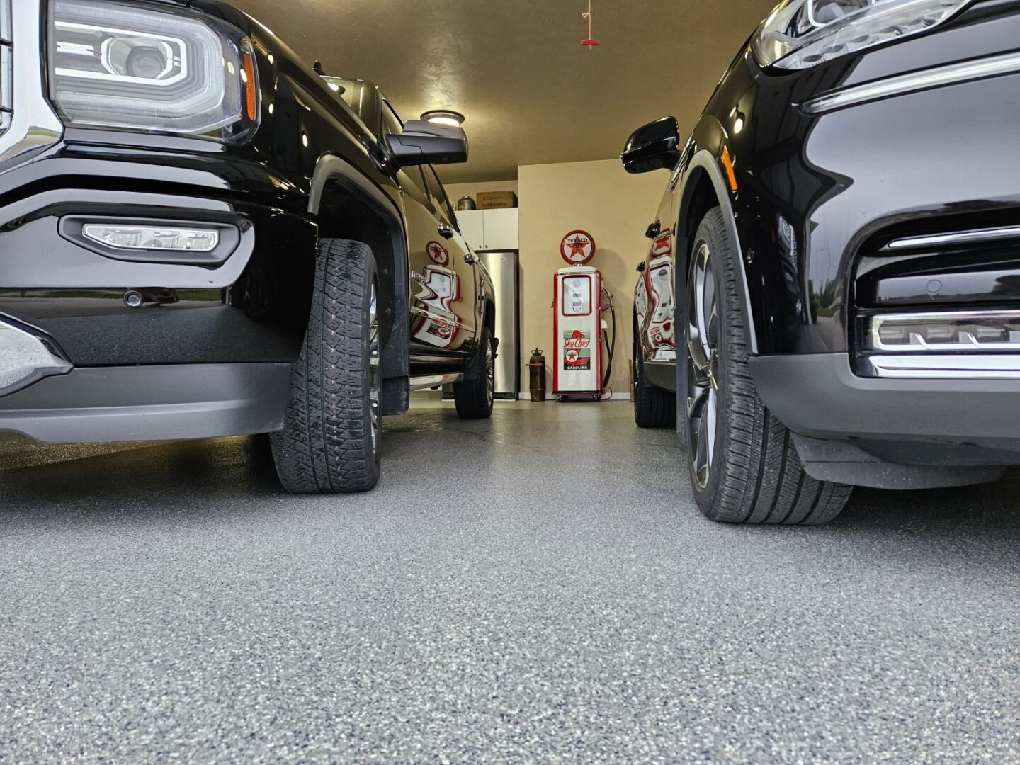 Two cars parked in a garage with their tires on the ground.